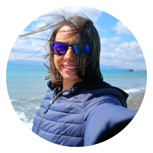 Frau mittleren Alters mit Sonnenbrille am Strand an der Nordsee lächelt in die Kamera