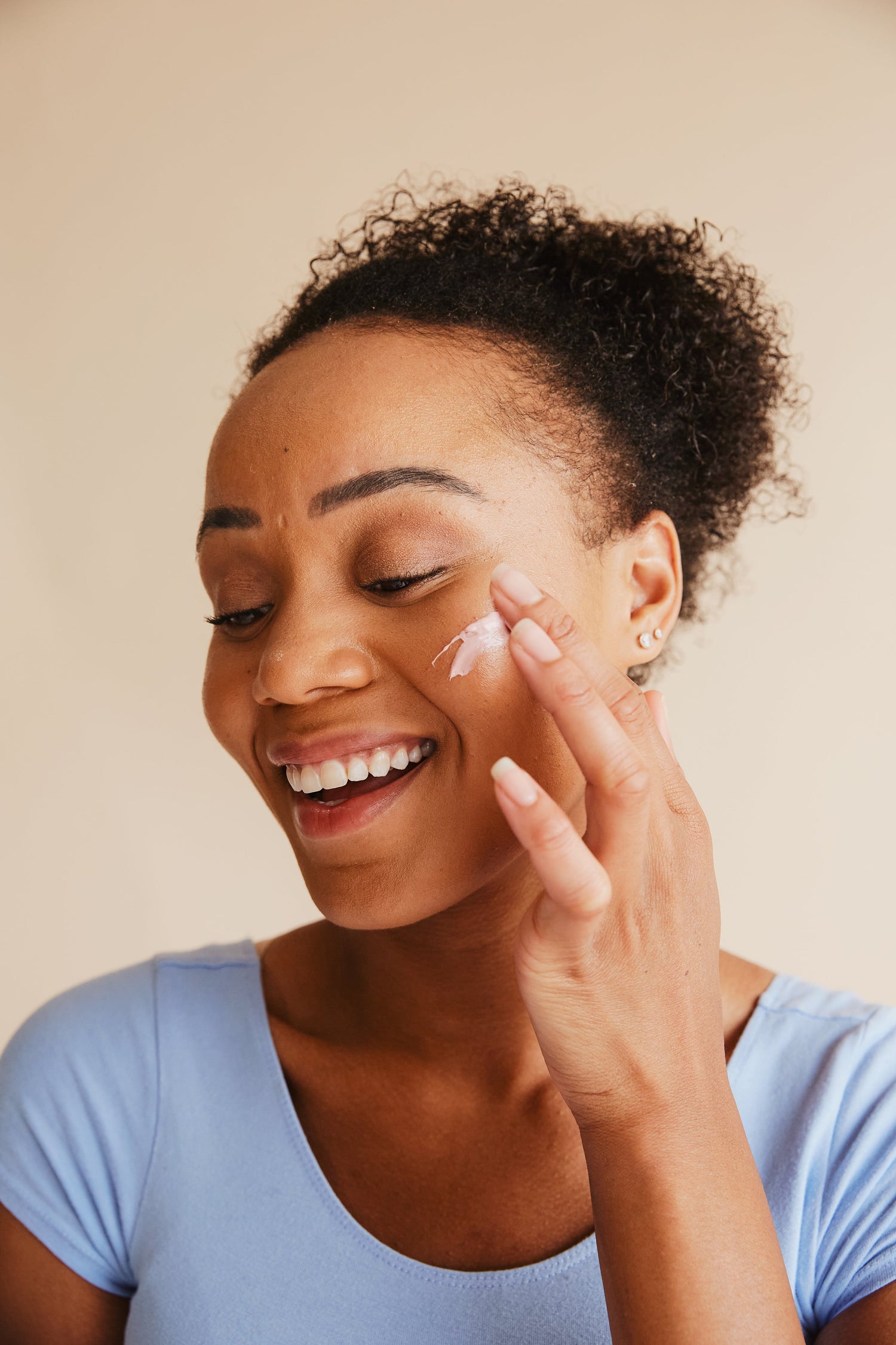 Frau schmiert sich ihre Creme die Sie bei Glowé im Onlineshop gekauft hat mi dem Finger auf die Wange